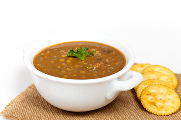 A cup of lentil soup with saltine crackers