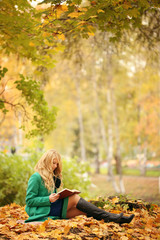 girl reading a book in autumn park