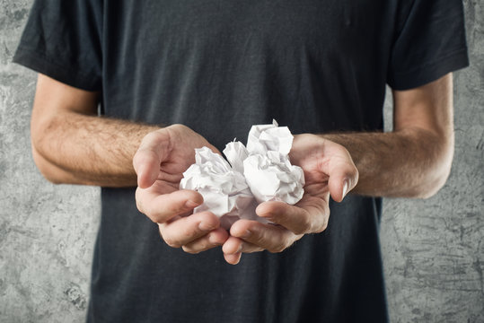 Man holding crumpled pieces of paper