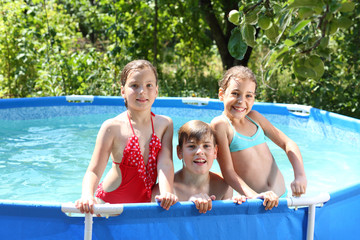 Three happy kids having fun in swimming pool on the courtyard
