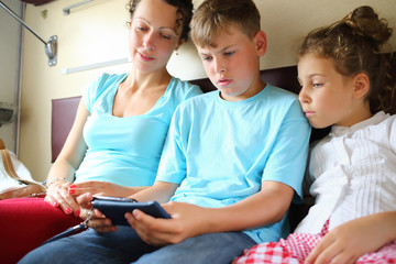 Woman and girl watching boy is playing with the phone