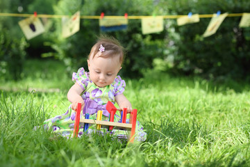 A little girl is playing with colorful wooden toys on the grass