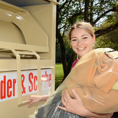 Frau bringt Altkleider zum Sammel-Container