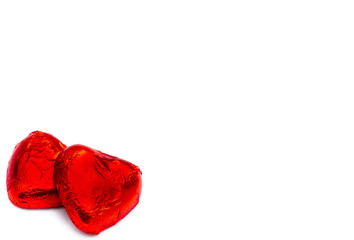 Two heart-shaped chocolate pieces on a white background, close-u