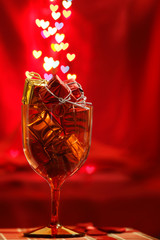 Festive background with glass, present boxes and hearts bokeh