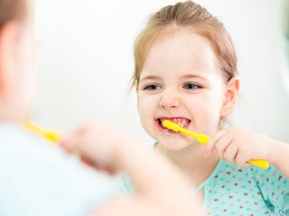 child girl brushing teeth in bathroom