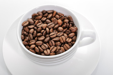 A cup full of coffee beans on a white background