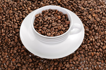 A cup full of coffee beans surrounded by more coffee beans