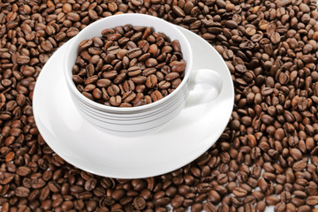 A cup full of coffee beans surrounded by more coffee beans