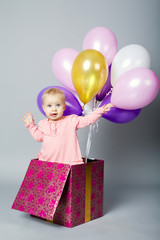 Fototapeta na wymiar cute little girl sitting on gift box with balloons