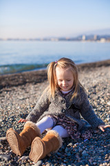 Adorable little girl on the beach having fun at warm winter day