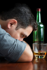 Depressed drunk man staring at a glass of scotch