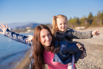 Young mother and adorable little daughter flying like a bird at