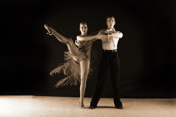 dancers in ballroom against black background