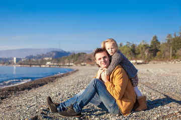 Fototapeta premium Young father and his little daughter at the beach on a sunny