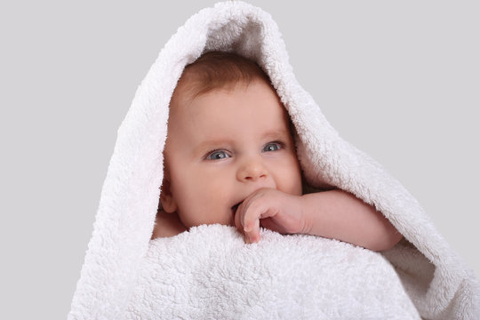 smiling cute baby in a white towel after bathing