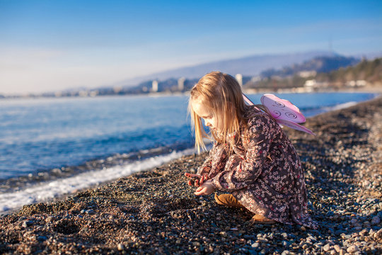 Adorable Little girl playing on the beach in a winter sunny day