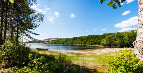 Panoramic view of a lake with boat from a forest in Northern Nor