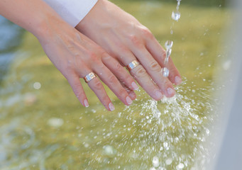 Hands of newly wedded under running water