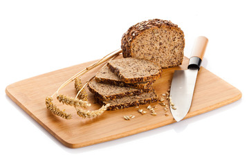 Fresh bread being sliced on a wooden cutting board with a bread