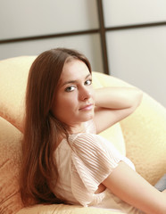 A young smiling woman sitting on the sofa at home