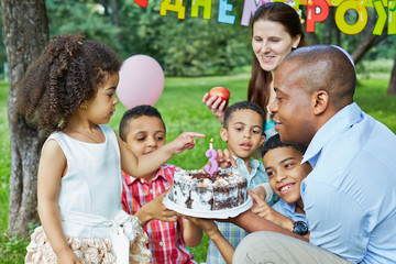 Father holds birthday cake with burning candle on it