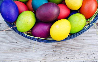 Colorful Easter eggs in basket on wooden background