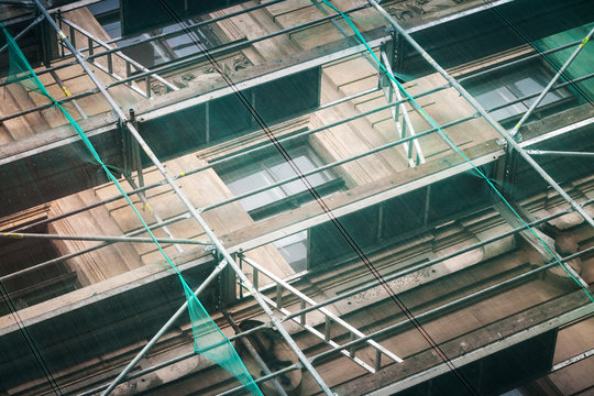 Old building facade under construction with green mesh