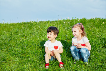 Two little children sit on edge of grassy slope