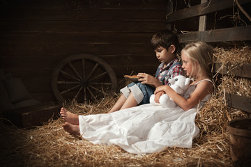 Children reading the book on the hay in the barn © Alexandr Vasilyev