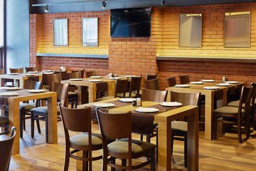 Interior of cafe-bar with wooden furniture and walls of bricks
