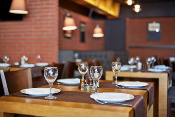 Room with served tables in restaurant, focus on glass in center