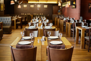 Roomy hall in restaurant with wooden furniture