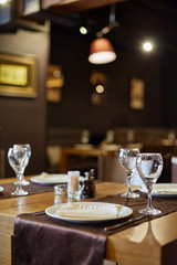 Served table in restaurant, focus on near glass and plate