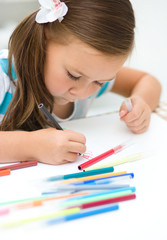 Little girl is writing using a pen