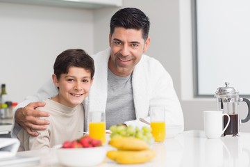 Obraz na płótnie Canvas Young son with father having breakfast in kitchen