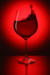 Glass of red wine on red background