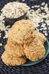 Oatmeal cookies on green plate, scattered oat flakes