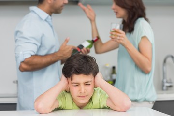 Obraz na płótnie Canvas Sad young boy covering ears while parents quarreling