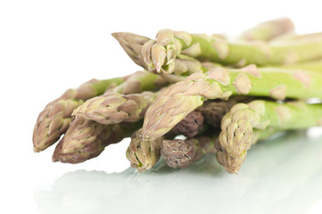 Bunch of fresh asparagus on a white reflective background.