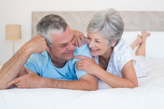 Senior couple smiling together on bed
