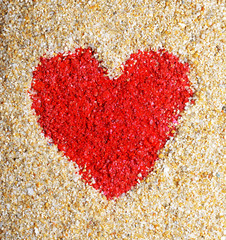 Red heart sign in yellow sand