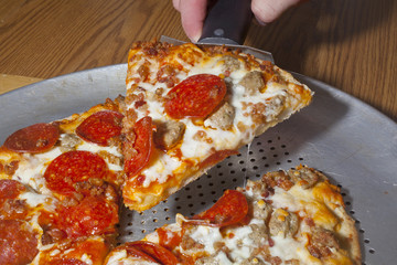 Serving a slice of meat lovers pizza.