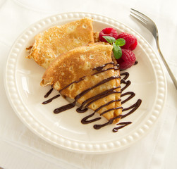 Delicious pancakes with berries and chocolate sauce.