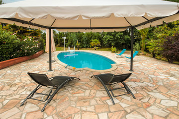 tonnelle et transats au bord de la piscine
