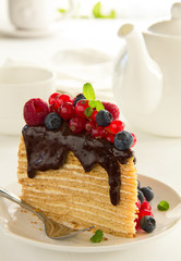 Piece of layer cake with chocolate sauce and berries.