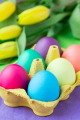 Colorful easter eggs in packing box with tulips flowers