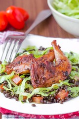 Delicious salad with black lentils, fried legs quail, tomatoes