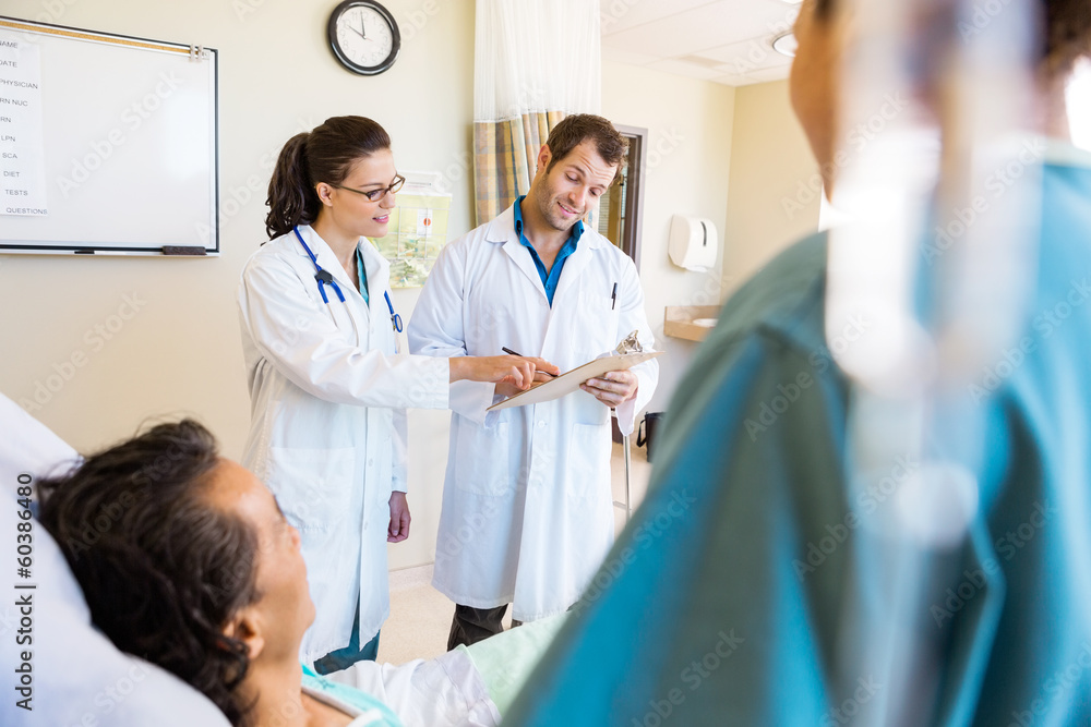 Wall mural doctors discussing notes with patient and nurse in foreground