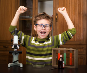 Happy boy with a microscope and colorful flasks. Education.